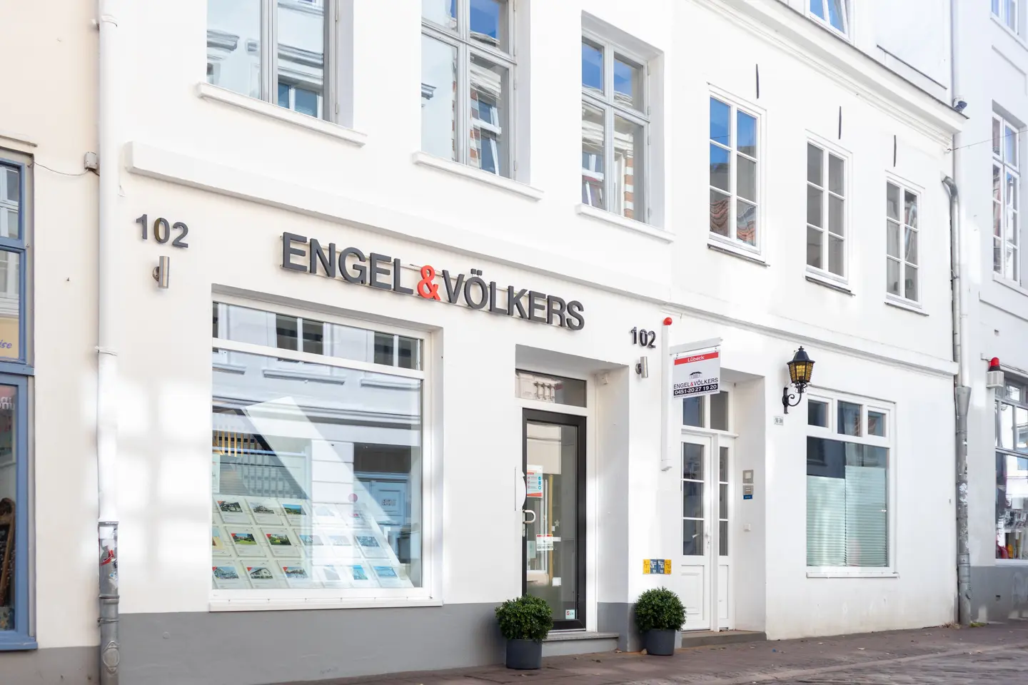 Engel & Völkers real estate office exterior. The white building has many windows and the company logo above the entrance.