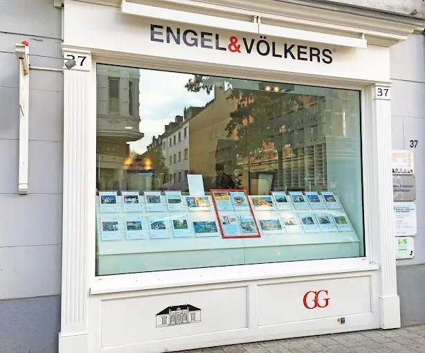 Engel & Völkers real estate storefront with property listings in the window. The building is white with black lettering.