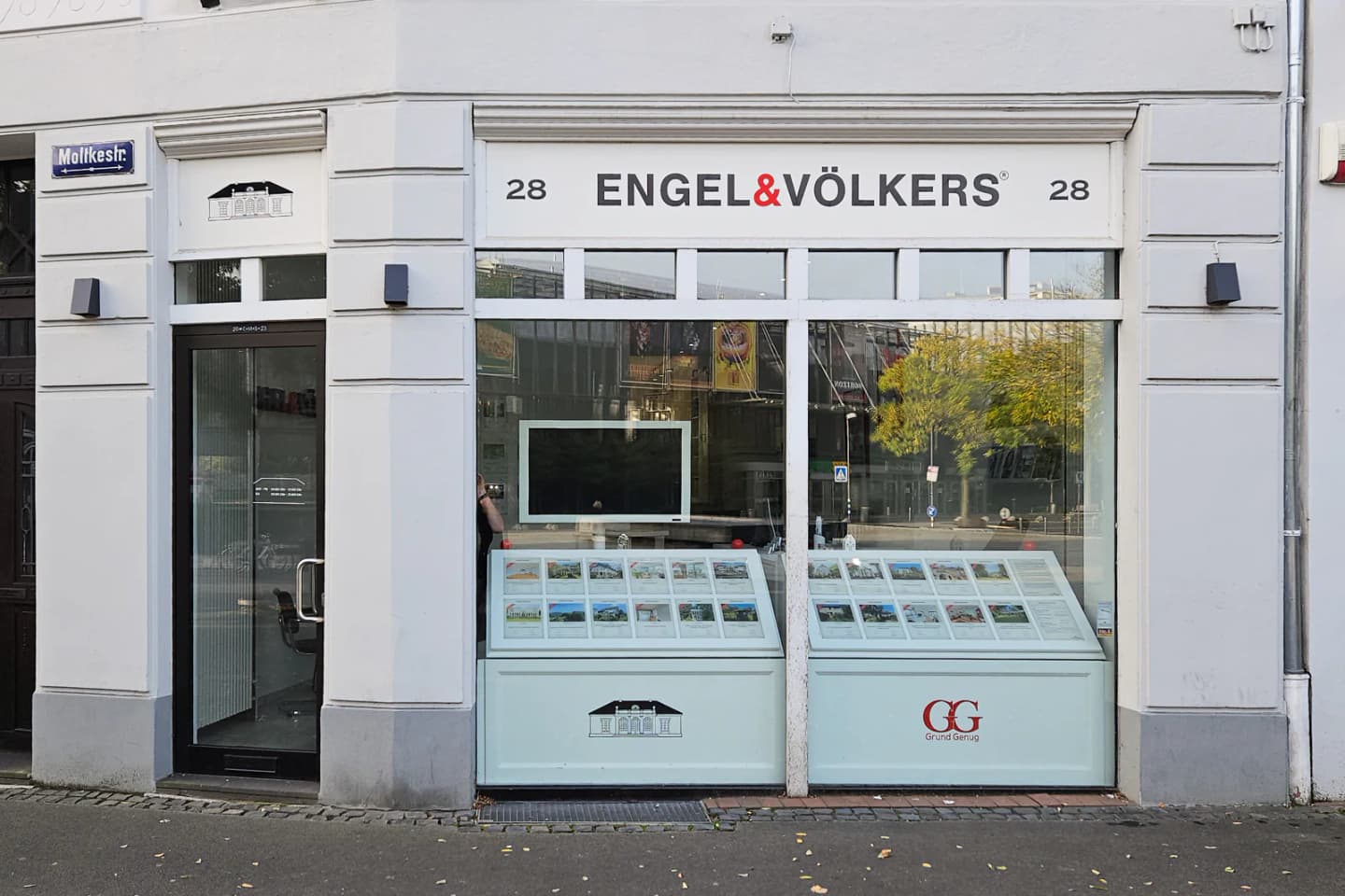 Exterior of Engel & Völkers real estate office with property listings displayed in the window.