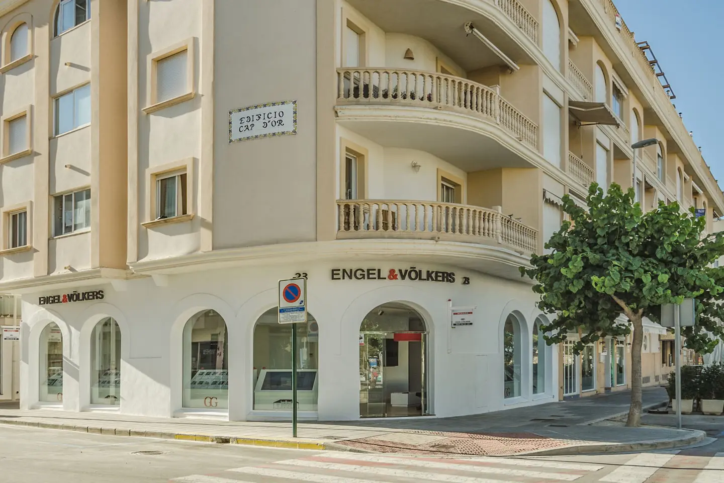 Vista exterior de l'oficina immobiliària d'Engel & Völkers en un edifici beix amb finestres arquejades i balcons.