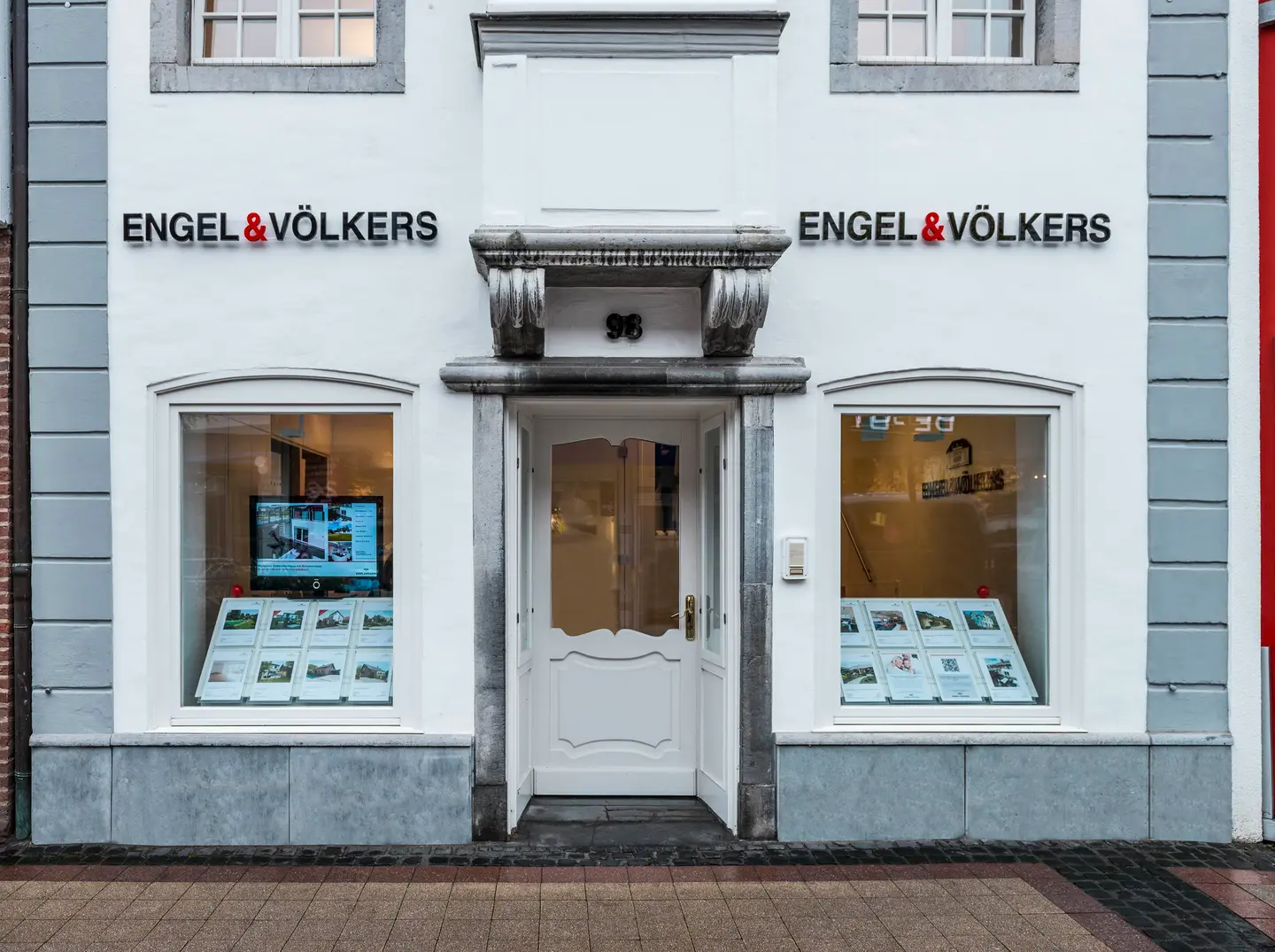 Engel & Völkers real estate office with white facade, grey trim, and window displays of properties.