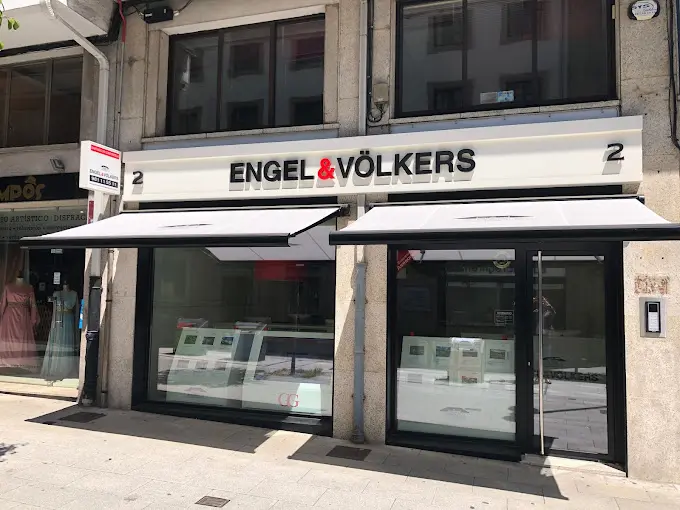 Vista exterior d'una immobiliària Engel & Völkers amb un tendal blanc i finestres amb marc negre.