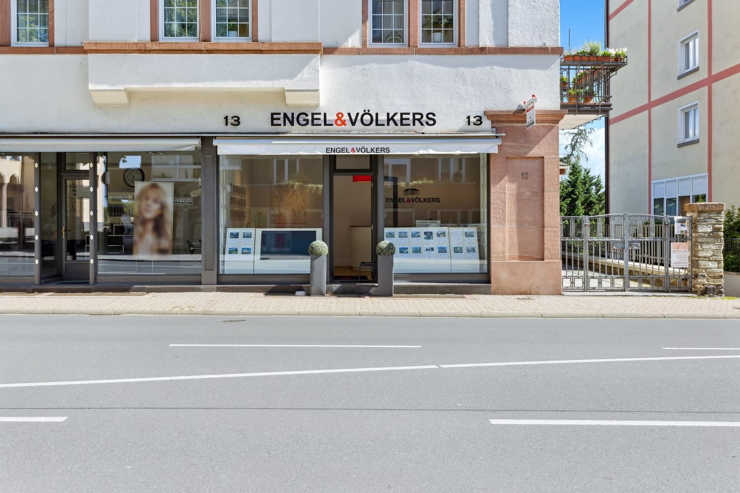 Engel & Völkers real estate office at street level. The building is white with brown trim and large windows.